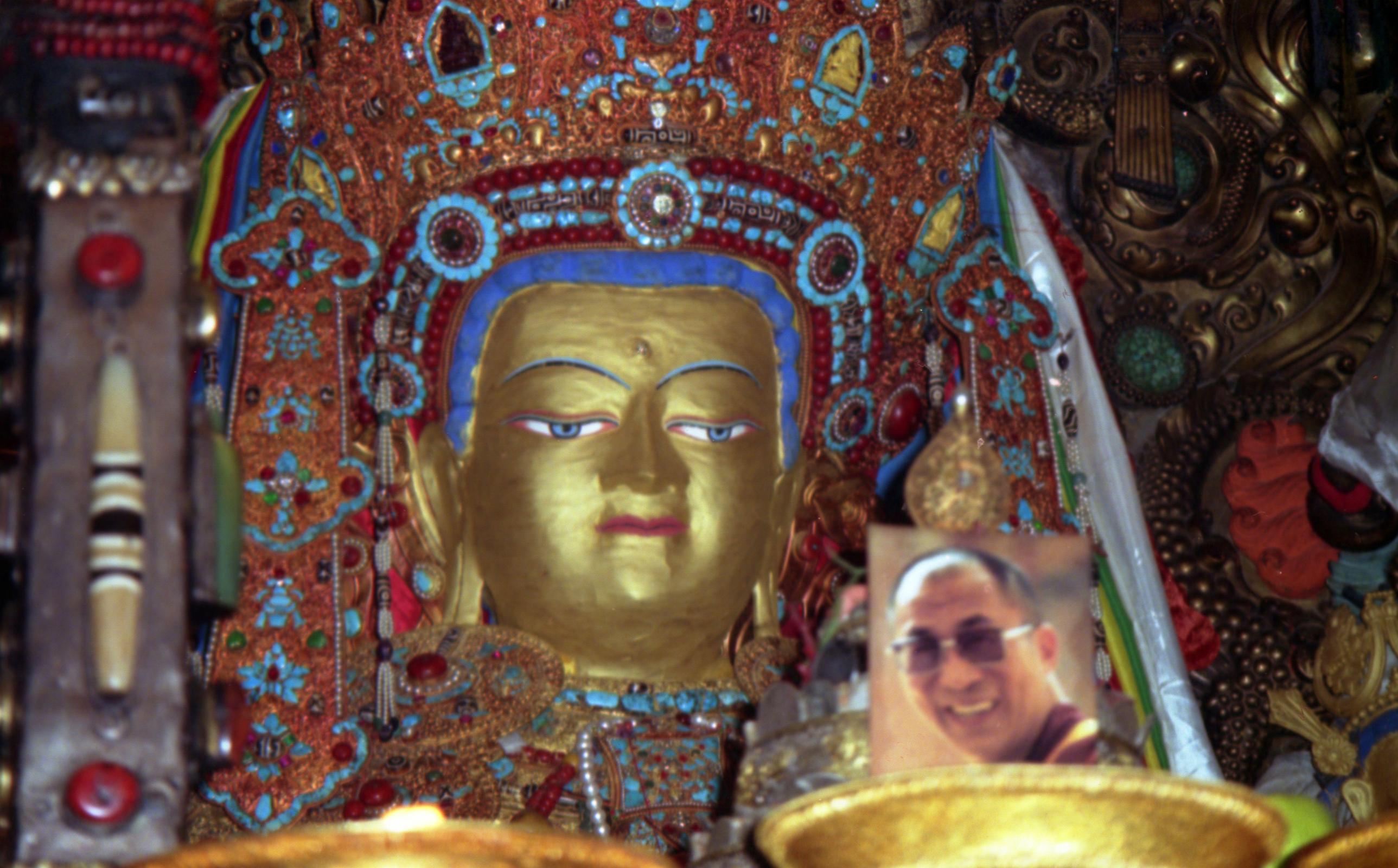 Tibet Lhasa 02 12 Jokhang Inside Jowo Shakyamuni The Chapel of Jowo Shakyamuni is the most important shrine in Tibet, housing a 1.5m sitting image of Shakyamuni at the age of 12. It is supposedly one of only three made during his lifetime. It was a gift from the Chinese Princess Wencheng to her husband King Songtsen Gampo. The Jowo sits on a majestic massive three-tiered stone platform. Two silver-plated dragons presented by the Chinese emperor entwine the ornate pillars that support an intricate double canopy over the Jowo. An ornate crown of coral, turquoise, diamonds, rubies, and other precious gems, sits on the Jowos head. Although theres no photography allowed, heres a photo from my 1993 trip. Note the photo of the current Dalai Lama, allowed in 1993 in a period of religious tolerance.